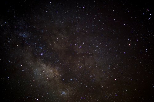 A starry night sky filled with countless stars and a faint glimpse of the Milky Way galaxy.