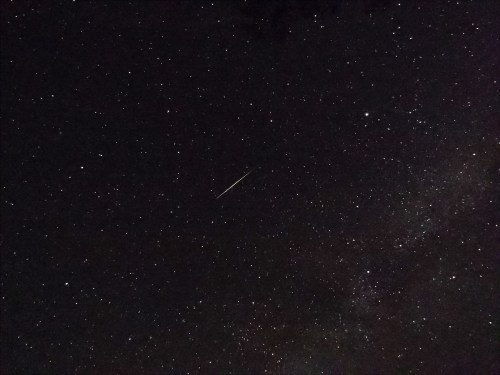 A starry night sky filled with countless stars and a bright meteor streaking across the scene.