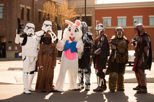A group of costumed characters, including Stormtroopers and a bunny, pose together in a sunny outdoor setting.