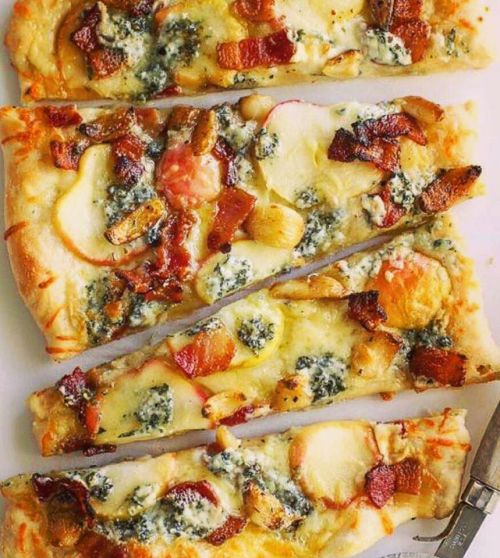 Four slices of pizza topped with blue cheese, bacon, and sliced potatoes on a white background.