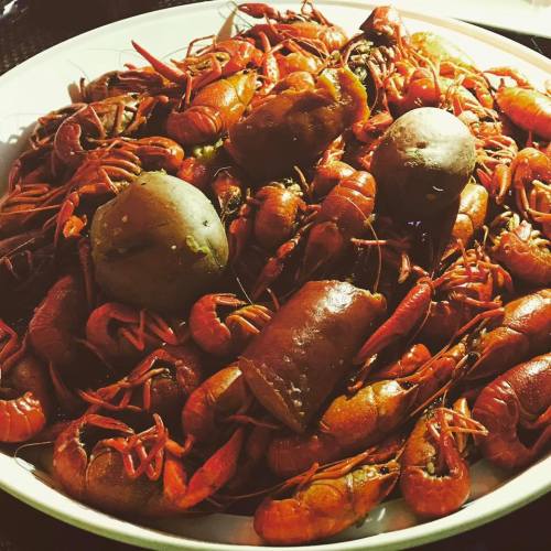 A large platter filled with cooked crawfish and potatoes, showcasing a vibrant red color and a hearty seafood feast.