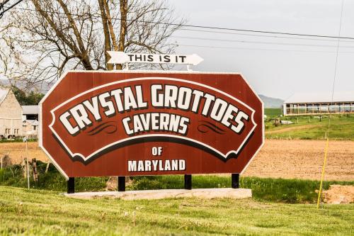 Sign for Crystal Grottoes Caverns of Maryland, featuring a large brown background with white text and an arrow pointing forward.