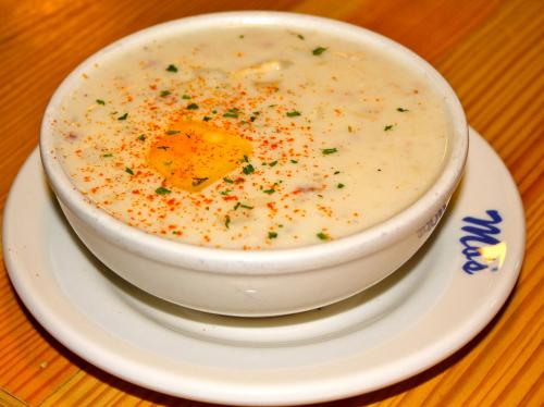A bowl of creamy soup topped with an egg yolk and sprinkled with paprika and herbs, served on a plate.