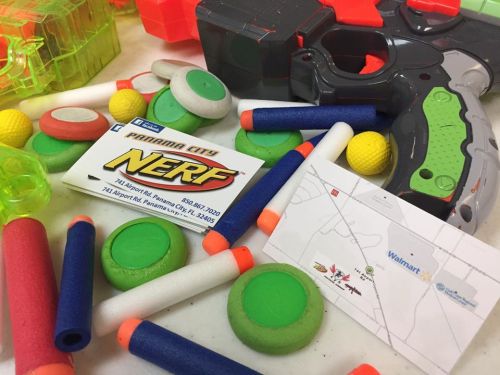 A collection of Nerf toys, foam darts, and maps, including a Walmart location and a Panama City Nerf card.