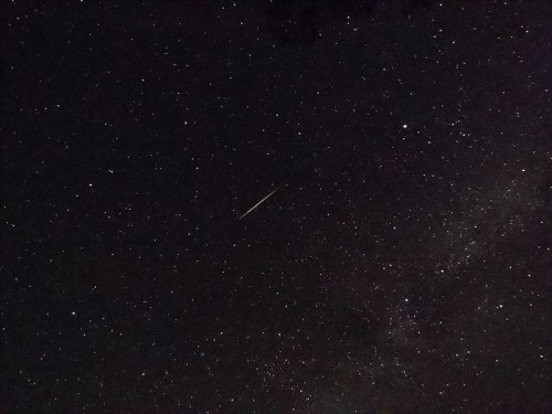 A starry night sky filled with countless stars and a bright meteor streaking across the scene.