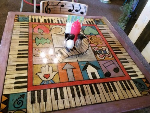 Colorful table design featuring a piano keyboard and various artistic patterns, with condiments in the center.