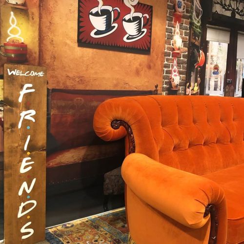 A cozy orange couch with a "Welcome Friends" sign in a vibrant, themed setting reminiscent of a popular TV show.