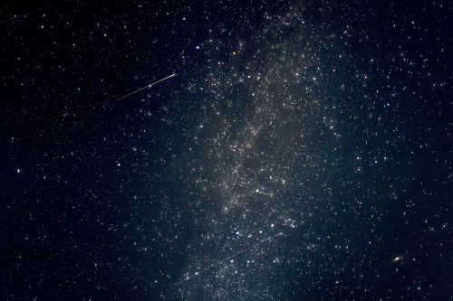 A starry night sky filled with countless stars and a few bright meteors streaking across the scene.