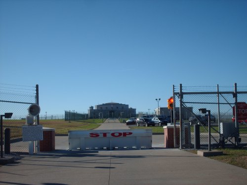 A view of a secure facility entrance with a "STOP" sign and a clear blue sky in the background.