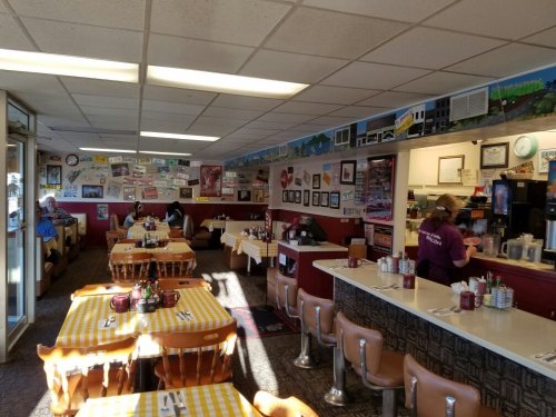 A cozy diner with checkered tablecloths, booths, and vintage decor, featuring a waitress serving customers.