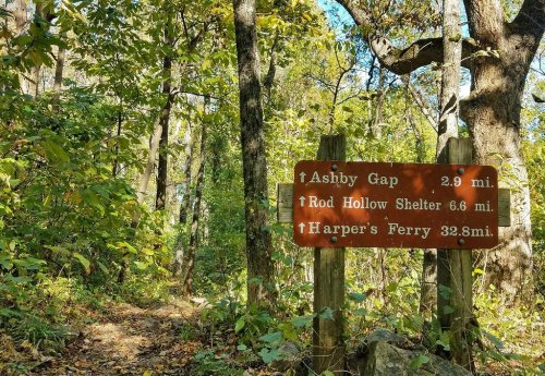 Trail sign in a wooded area, indicating distances to Ashby Gap, Rod Hollow Shelter, and Harper's Ferry.