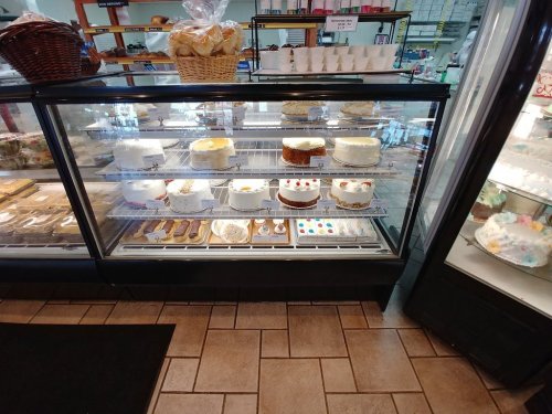 A display case filled with various cakes and pastries, showcasing colorful desserts and decorated cakes.