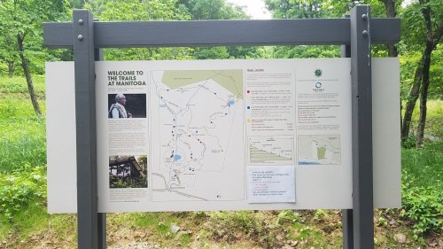 Signboard displaying a map and information about the trails at Maintoga, surrounded by greenery.