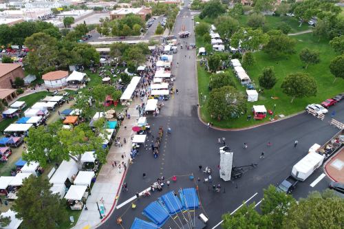 Aerial view of a bustling outdoor event with tents, vendors, and people enjoying the festivities in a green park area.