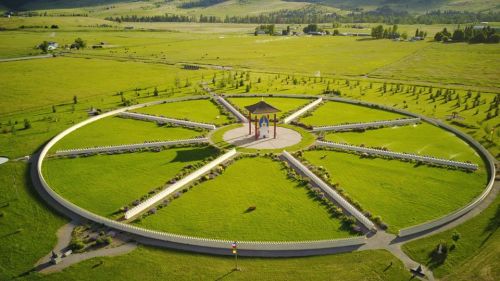 Aerial view of a circular park with a gazebo at the center, surrounded by green fields and neatly arranged pathways.