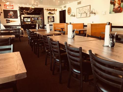 Interior of a restaurant featuring wooden tables, black chairs, and a cozy atmosphere with decorative elements.