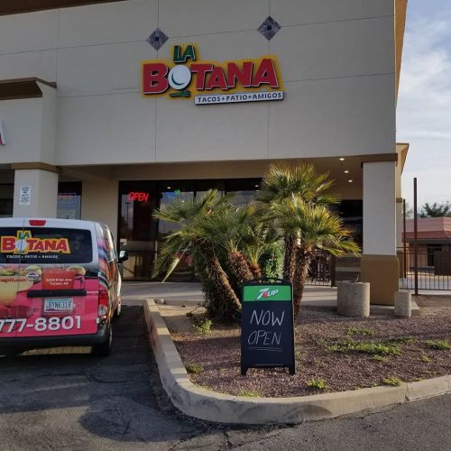 Exterior of La Botana restaurant with a sign reading "NOW OPEN" and a colorful delivery vehicle parked outside.