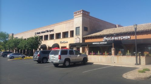 A sunny day view of a building with a restaurant called "Sole Kitchen" and parked cars in the foreground.
