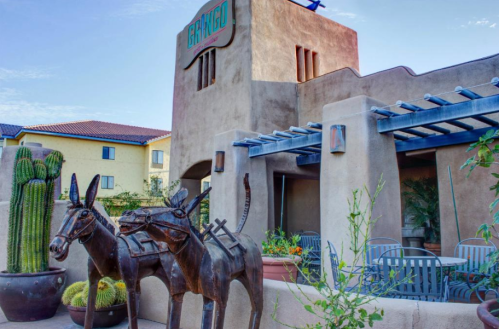 A southwestern-style building with a sign reading "San Diego," featuring metal donkey sculptures and cacti.