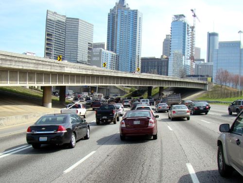 Busy highway with heavy traffic, surrounded by tall buildings and construction in an urban setting.