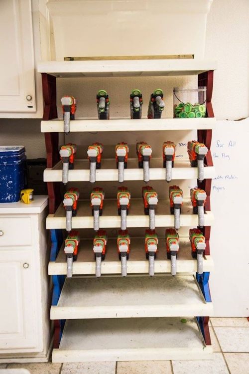 A shelf displaying multiple tape dispensers arranged in neat rows, with a white wall and cabinets in the background.