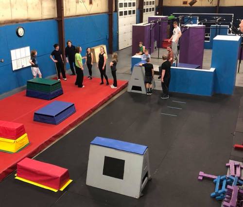 A gym with various obstacle courses; people practicing parkour and movement skills on colorful equipment.