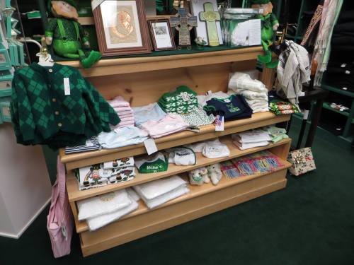 A wooden display shelf filled with various clothing items and decorations, including sweaters and holiday-themed apparel.