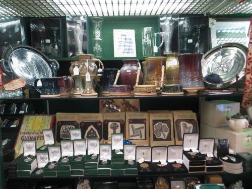A display of various decorative glassware and metal items, including vases, plates, and jewelry in a shop setting.