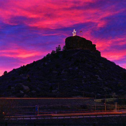 A star atop a rocky hill against a vibrant pink and purple sunset sky.