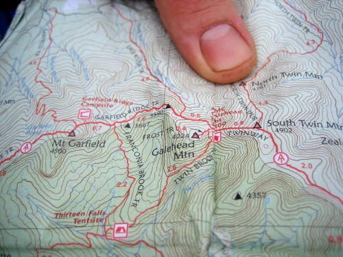 A close-up of a topographic map with a finger pointing at a location near Galhead Mountain.