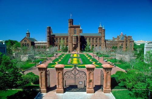 The Smithsonian Institution building surrounded by vibrant gardens and clear blue skies.