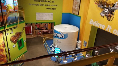 A colorful indoor exhibit featuring a large white cylinder labeled "Garmin" and various art pieces on the walls.