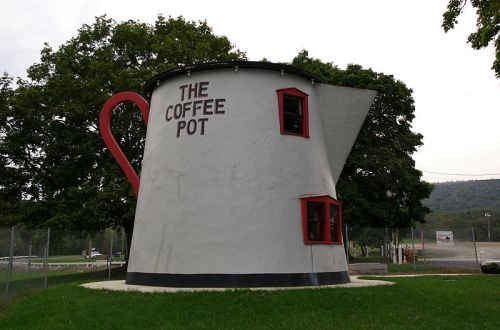 A large, whimsical building shaped like a coffee pot, featuring a handle and the words "THE COFFEE POT" on its side.