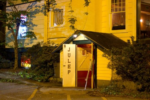 A dimly lit entrance to a building labeled "Julep," surrounded by trees and a parking area at night.
