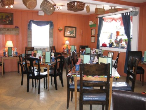 Cozy restaurant interior with wooden tables, chairs, and colorful decor, featuring warm lighting and wall art.