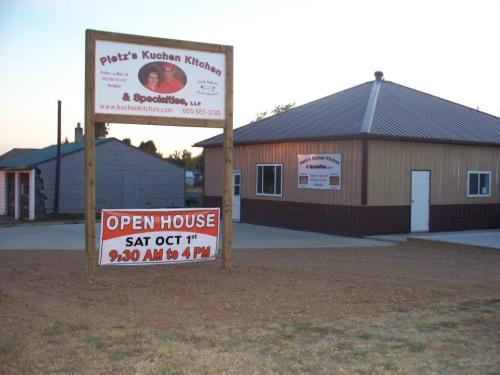 Sign for Pietz's Kuchen Kitchen with an open house announcement for October 1st, 9:30 AM to 4 PM. Building exterior visible.