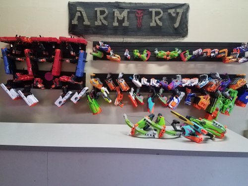A display of various toy blasters arranged on shelves, with a sign reading "ARMORY" above them.