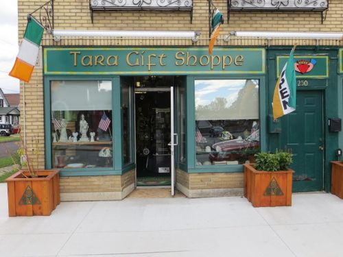 Exterior of Tara Gift Shoppe with Irish and American flags, showcasing a welcoming entrance and decorative planters.