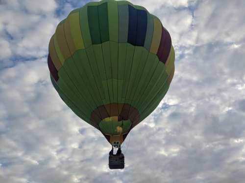 A colorful hot air balloon floats against a backdrop of cloudy skies.