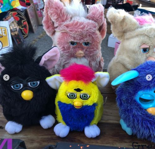 A collection of colorful, furry toy creatures with various expressions, including a black, yellow, and blue one.