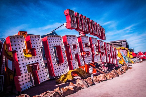 Colorful vintage neon signs spelling "Bunny's Horseshoe" against a bright blue sky, with rocks in the foreground.