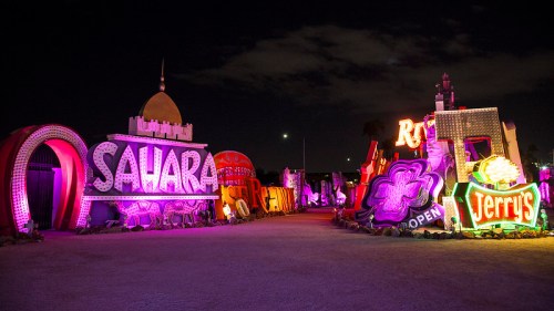 Colorful vintage neon signs from Las Vegas, including "Sahara" and "Jerry's," illuminated at night.