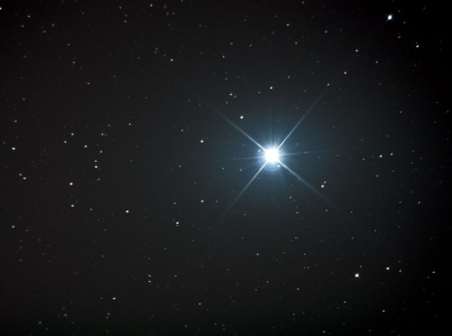 A bright star shines in a dark sky filled with scattered stars, creating a stunning celestial scene.