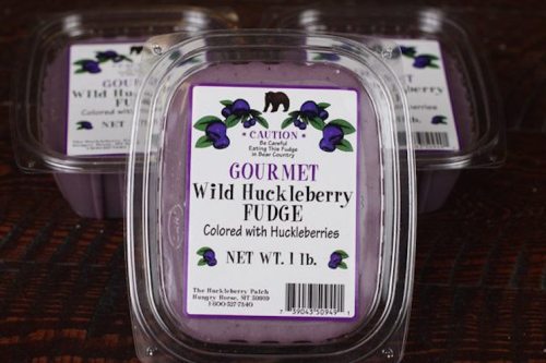 Container of gourmet wild huckleberry fudge, featuring a purple color and a label with huckleberries and a bear warning.