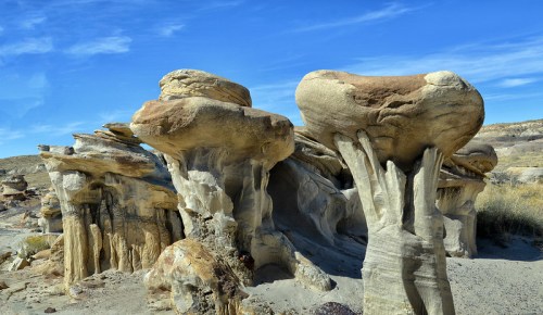 Unique rock formations with mushroom-like caps against a clear blue sky in a desert landscape.