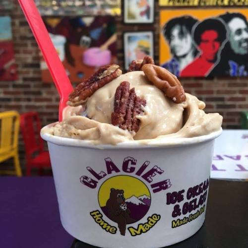 A cup of homemade ice cream topped with pecans, set against a colorful, artistic background.