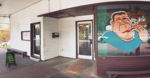 A storefront with a cartoon character on the window, advertising pizza, and a sign outside.