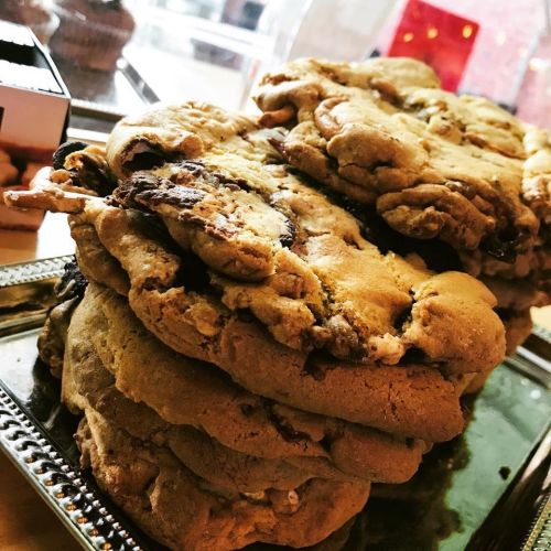 A close-up of a stack of large, freshly baked cookies on a silver tray.