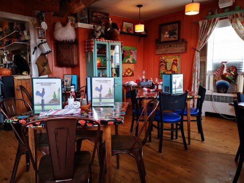 Cozy restaurant interior with colorful decor, wooden tables, and menus featuring a rooster design.