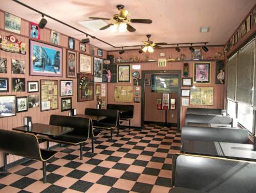 Cozy diner interior with checkered floor, black booths, and walls adorned with framed photos and memorabilia.